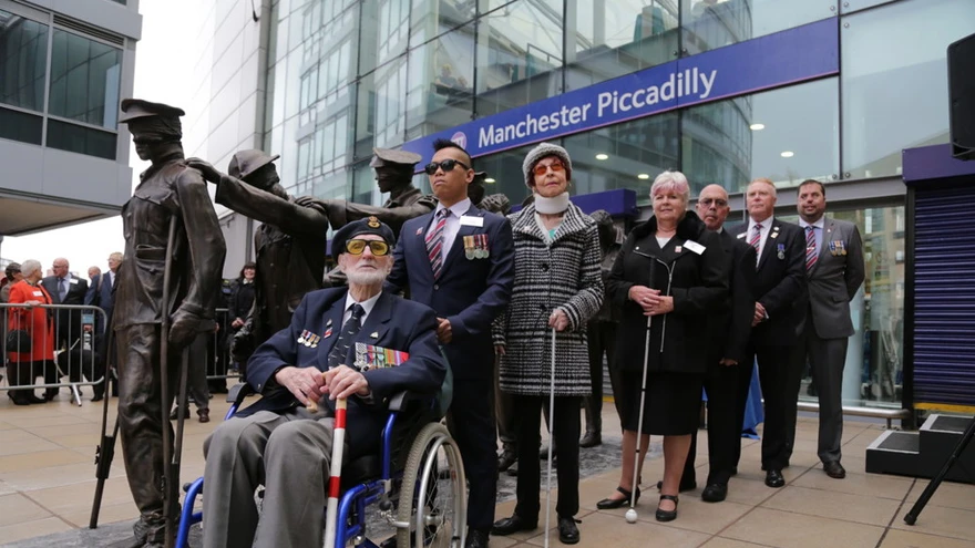 Seven blind veterans next to our Victory Over Blindness statue outside Manchester Piccadilly station