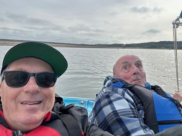 Terry and Simon smile and look into the camera while on their Hansa 303 boat