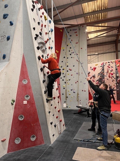 Jill halfway up an indoor climbing wall
