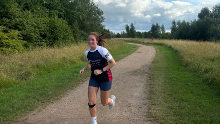 Grace is running along a gravel path wearing her Blind Veterans UK t-shirt