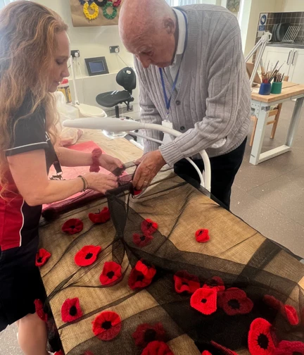 A blind veteran and staff member n the studio attached poppies to the netted poppy blanket