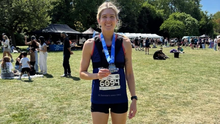 Steph with her medal around her neck stood in a field after the race