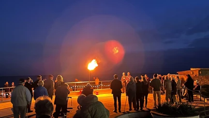 A group of people watch as a large beacon is lit against the night sky at the Rustington Centre.