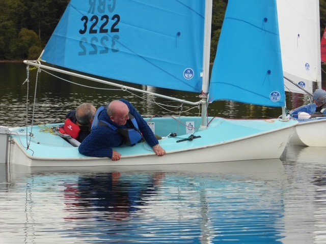 Simon and Terry are on a Hansa 303 boat on the water and Simon leans over the edge