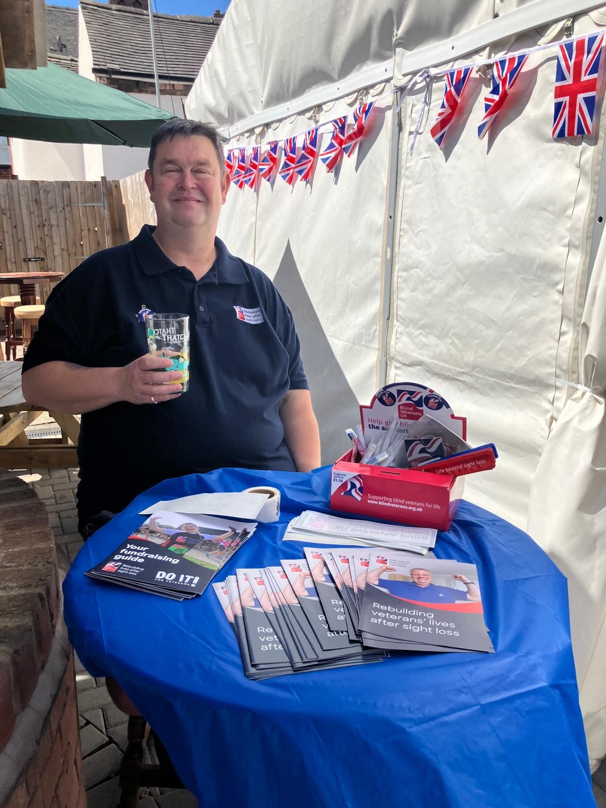 Clive sat at a table with Blind Veterans UK information leaflets
