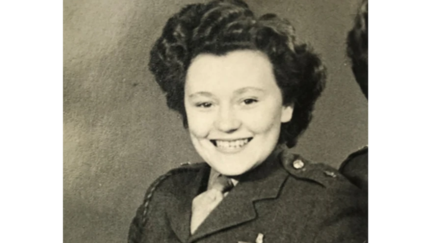A black and white portrait of Neena during her military service, smiling in military uniform.