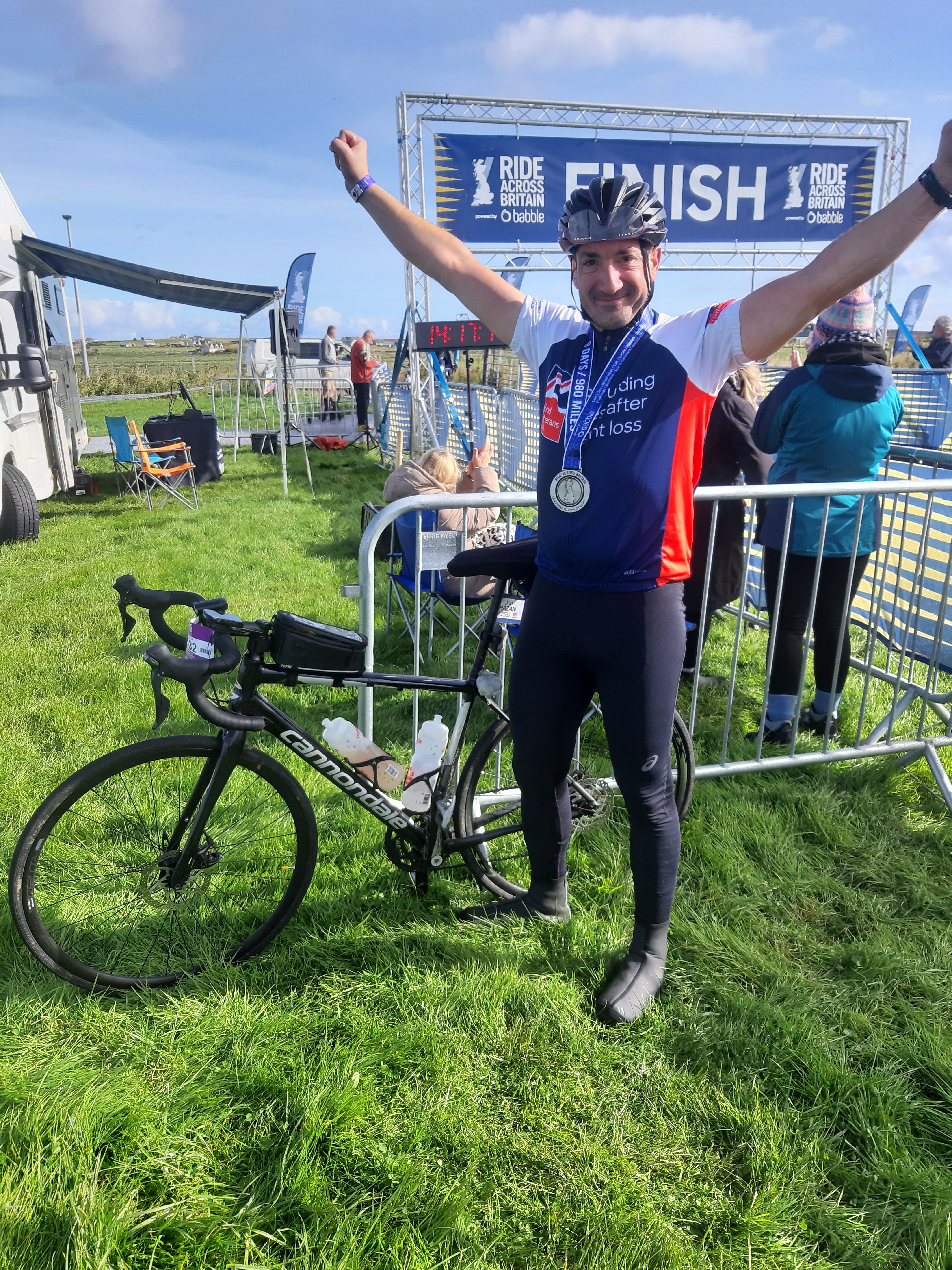 Jon celebrating with his arms in the air and medal around his neck