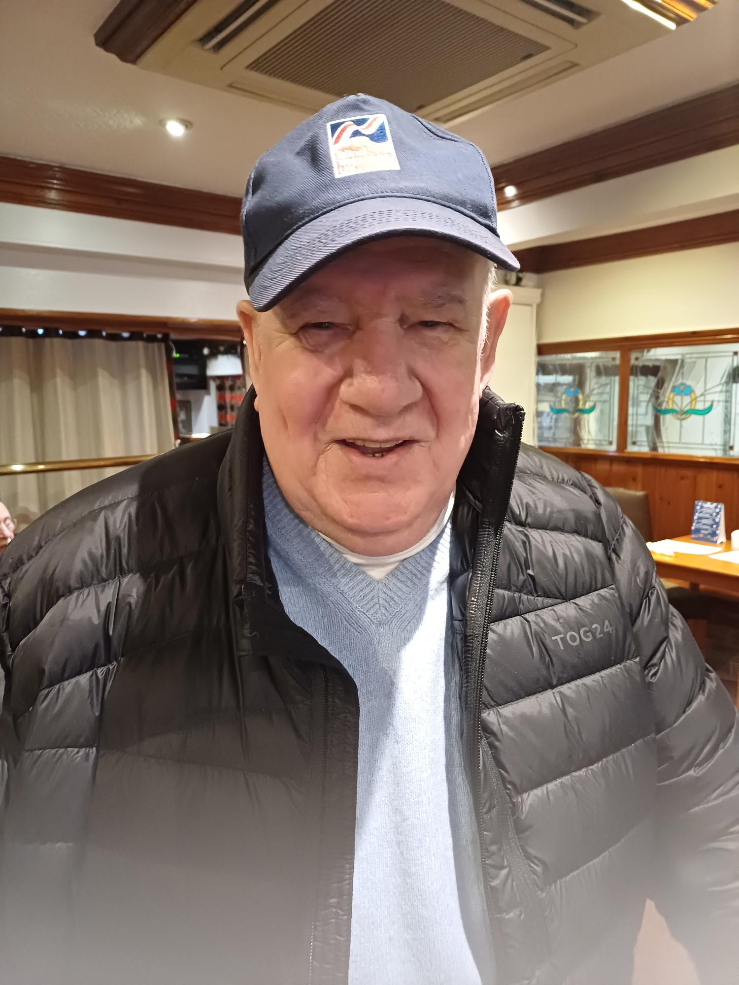 Jim wears a cap and body warmer and looks into the camera