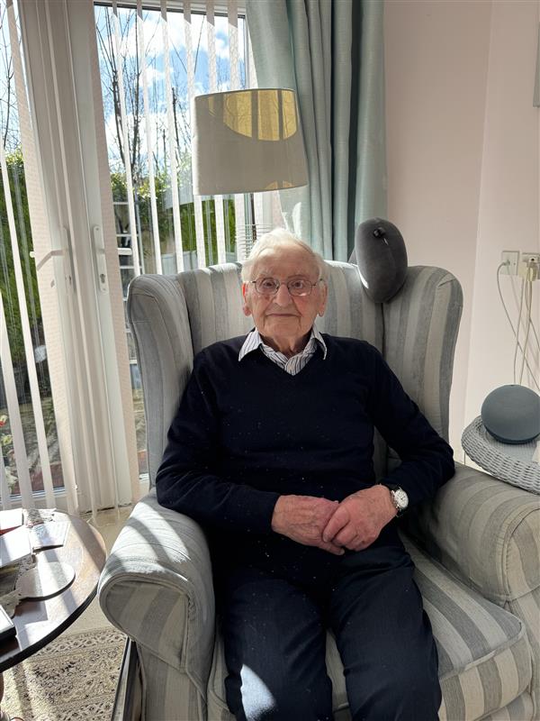 A photo of John sitting in a chair with french doors behind him