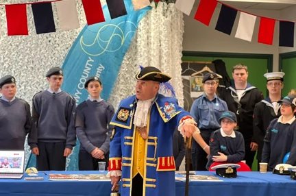 Billy in his town crier coat stood with uniformed sea cadets at their table with information leaflets about their organisation