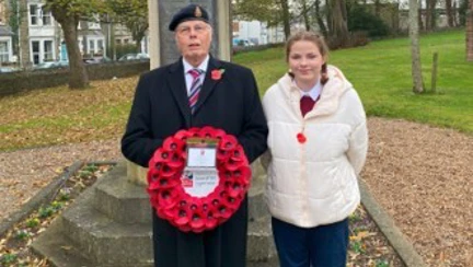 Howell and his granddaughter stand in front of the war memorial in Porthcawl with Howell holding his wreath
