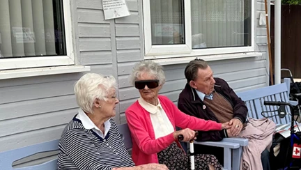 Three veterans sitting on a bench spectating at the bowls event
