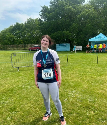Megan wearing her Blind Veteran UK running top standing proudly with her medal around her neck