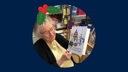 Blind veteran Joan wearing a Christmas hat, detailed with an illustration of holly.