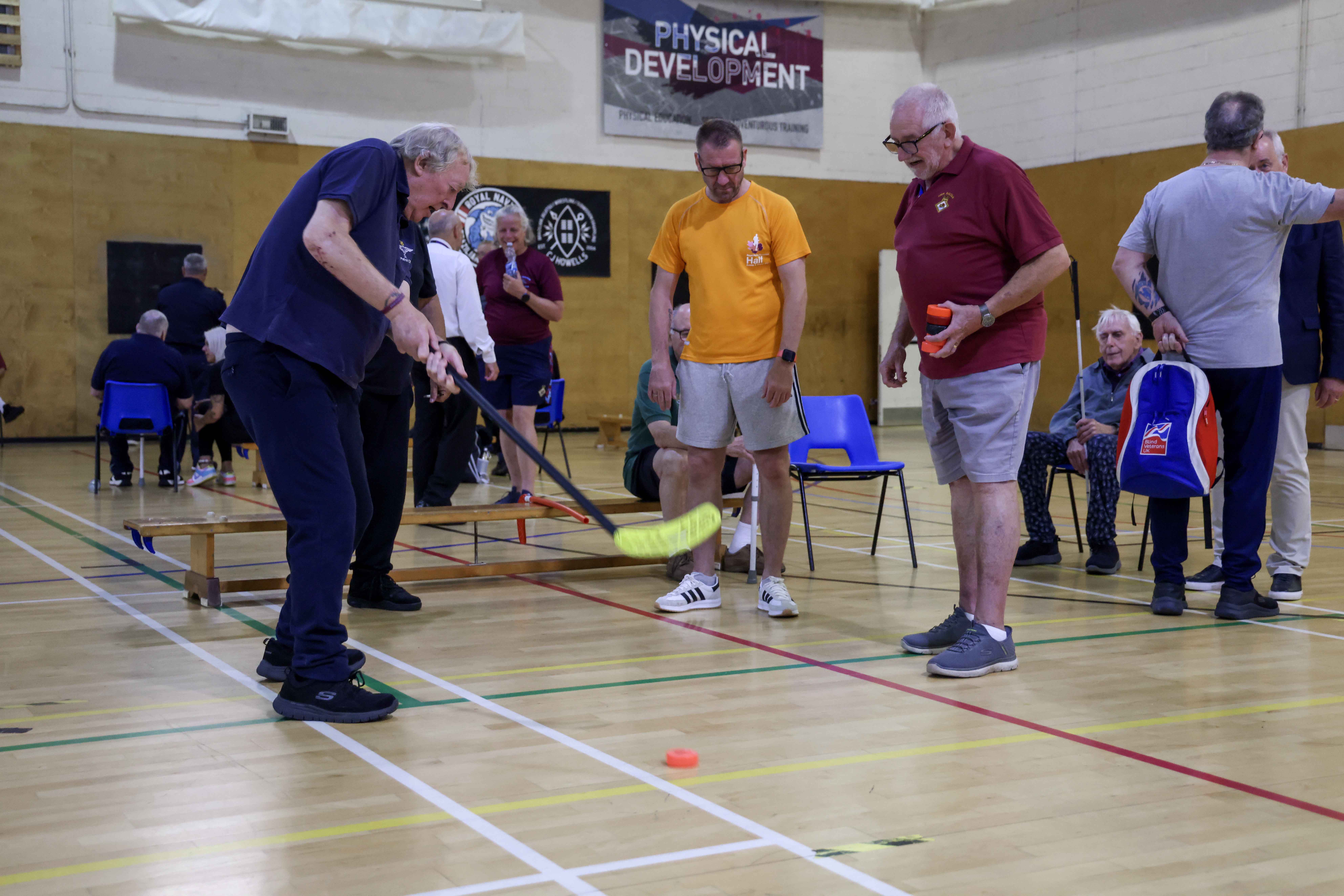 Two blind veterans partake in a hockey based activity with a guide