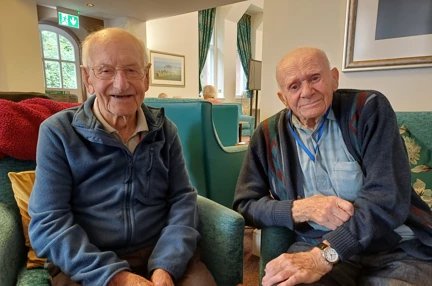 Joe and Arthur sit next to each other and look into the camera at our Llandudno Centre