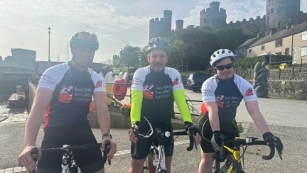 The three cyclists on their bikes with Conwy Castle in the background
