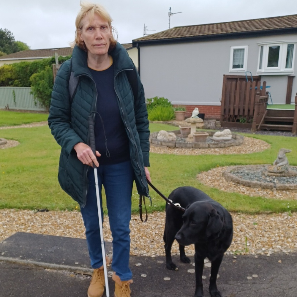 Blind veteran Jill standing with her cane and dog