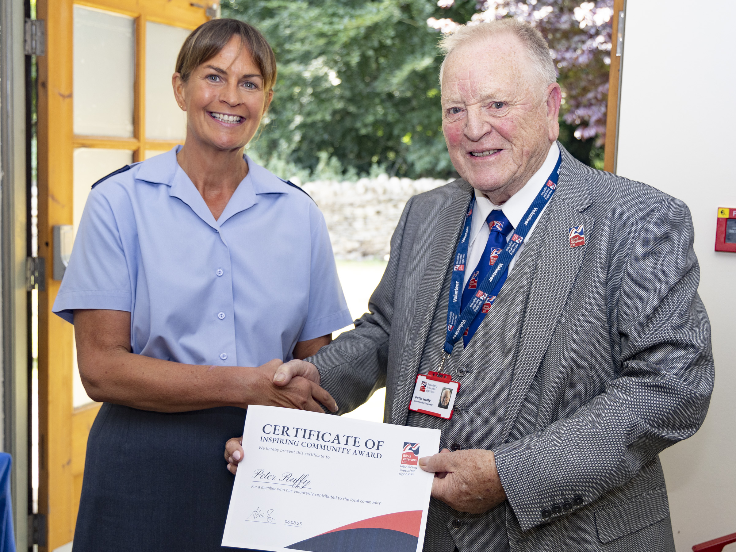 Peter shakes hands with WO Tracey Kenworthy as she delivers his certificate. They are both smiling. 