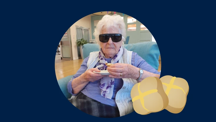Blind veteran Betty holding a hot cross bun, with an added illustration of a hot cross bun