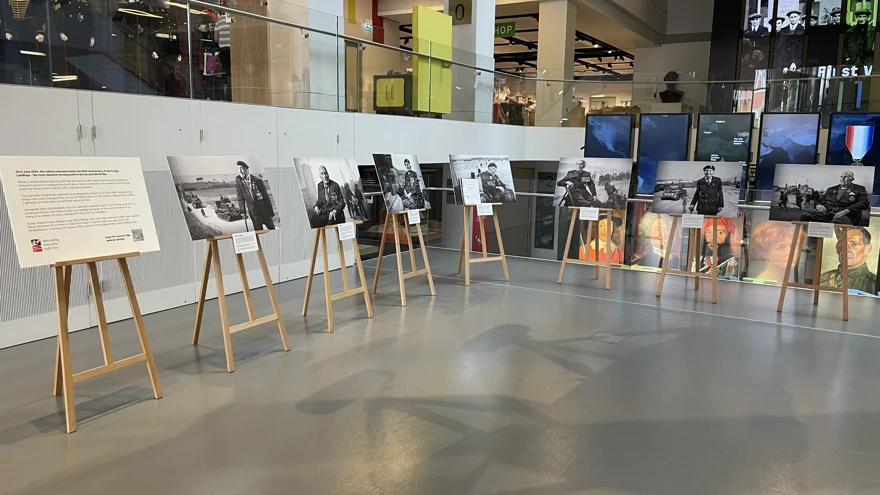 Seven black and white large canvas photographs displayed on easels in an exhibition space