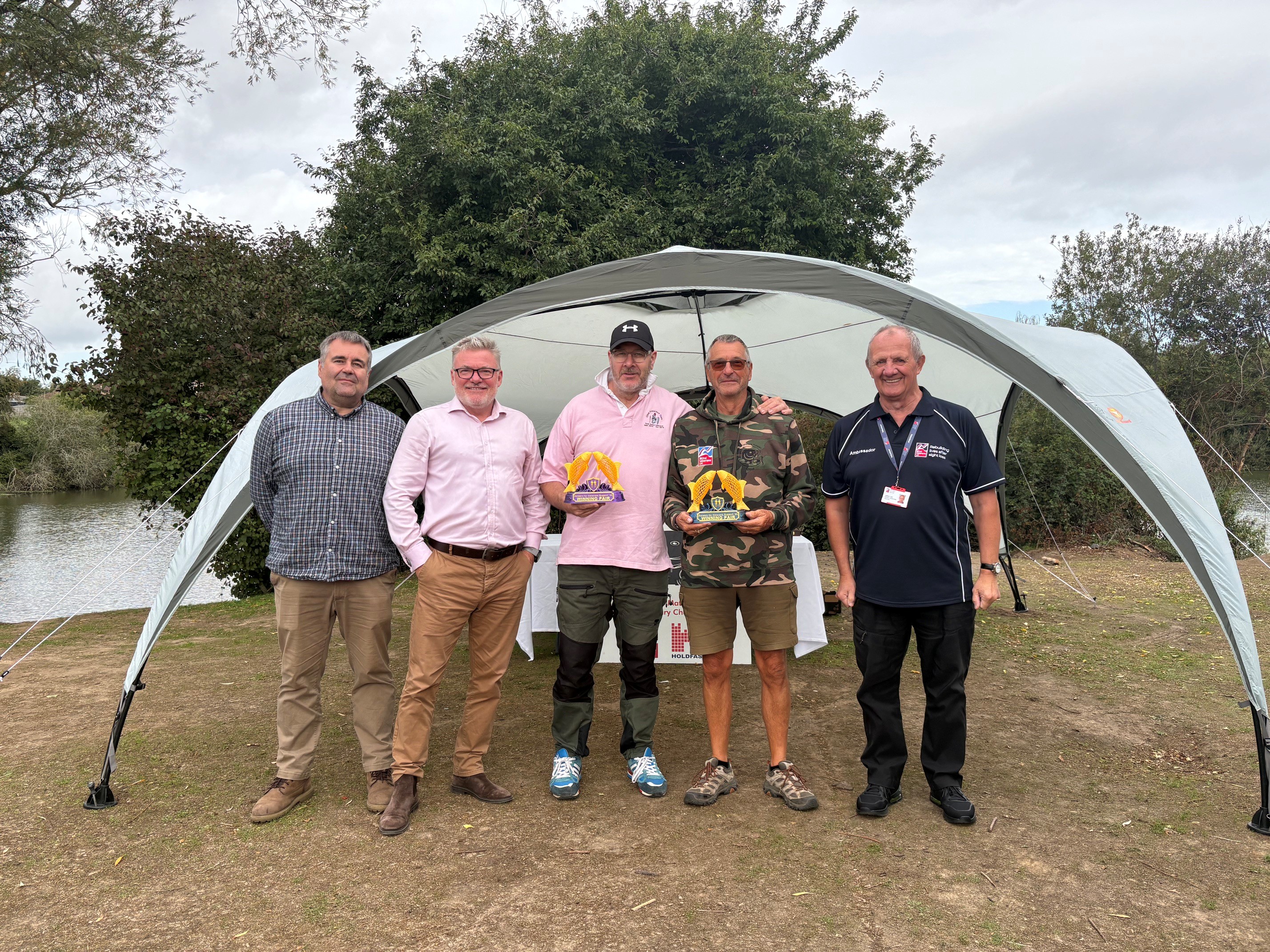 A group picture of John and Mark from Holdfast Training with Jase and Steve who won this year's competition and are holding their winner's trophies and blind veteran Jules
