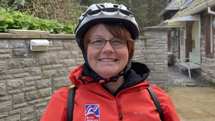 Blind veteran Sheila wearing a cycling helmet and red Blind Veterans UK jacket