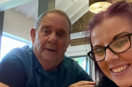 A selfie taken of Rebecca with Brian as they are sat at a table
