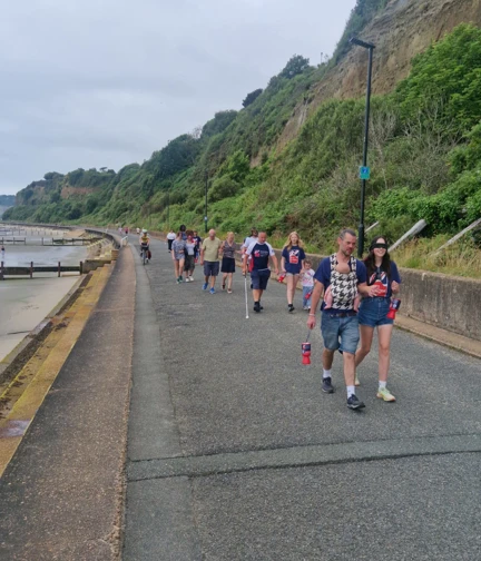 The blindfolded walkers are guided along the coastal path with cliffs to one side of them and the sea on the other