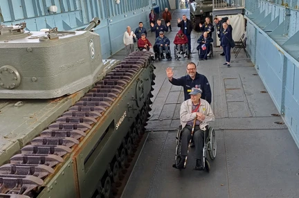 A photo of blind veterans looking at a D-Day museum landing craft