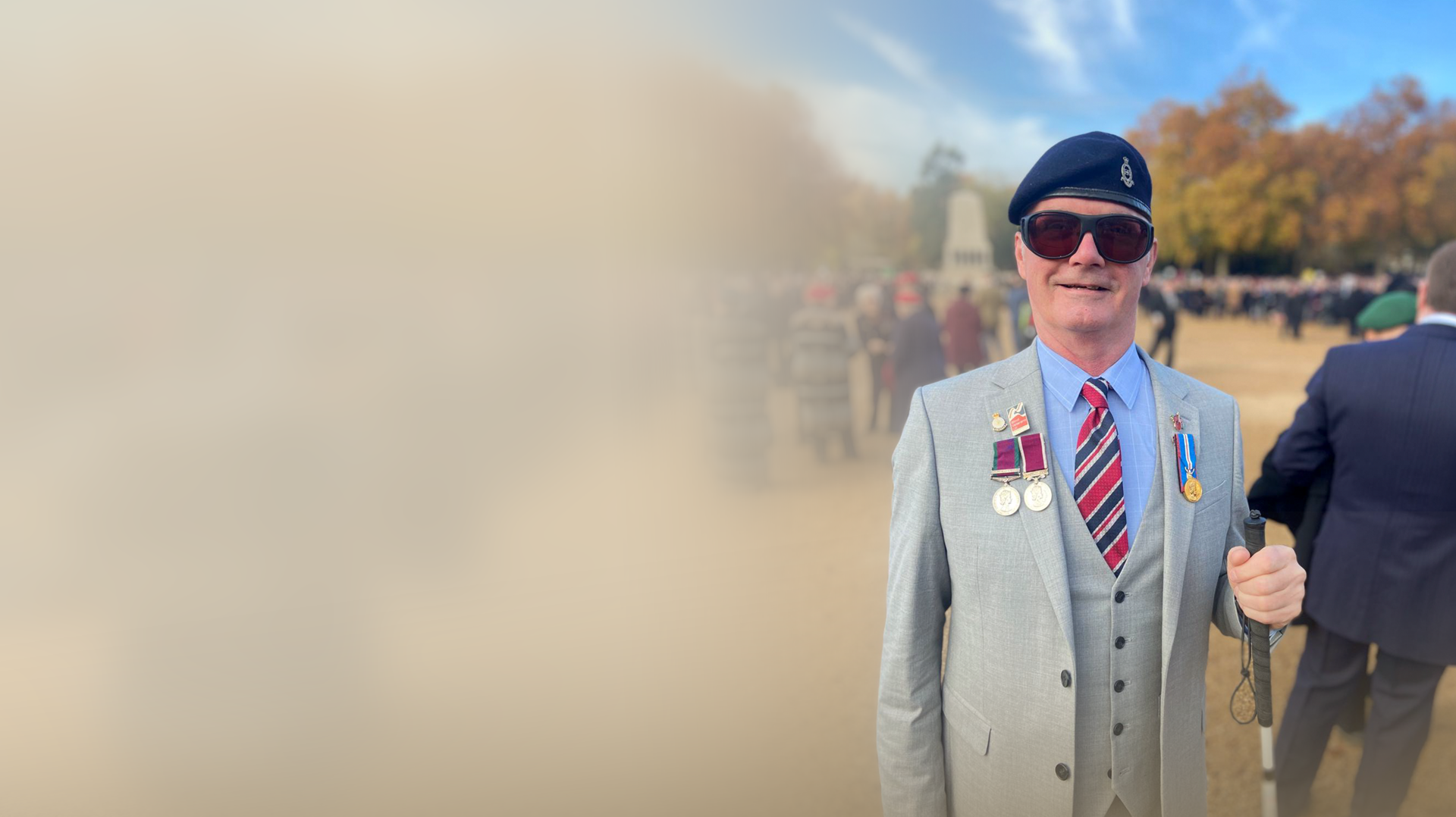 Photo of a blind veteran Mark standing at the London Cenotaph with a white cane