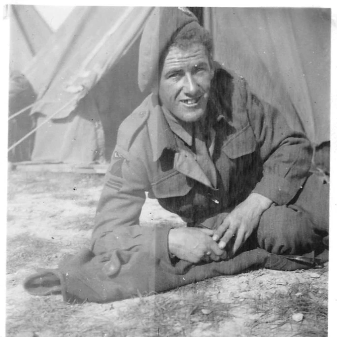 A young Harry, pictured in the 1940s wearing his military uniform, seated casually outside a tent.