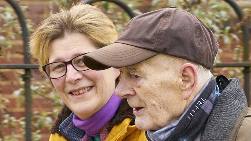 A headshot of blind veteran Colin and his daughter smiling at the camera as they walk