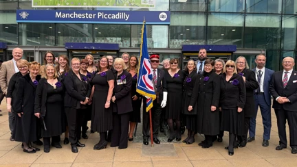 A group photo of the Military Wives Choir and Blind Veterans UK staff at Manchester Piccadilly station.
