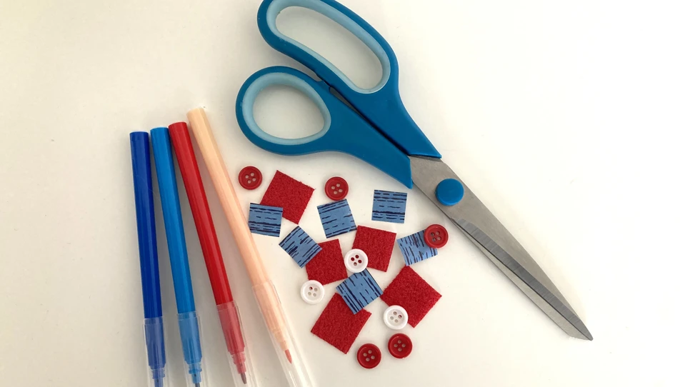 Red, white and blue craft materials; felt-tip pens, paper squares, buttons and a pair of scissors.