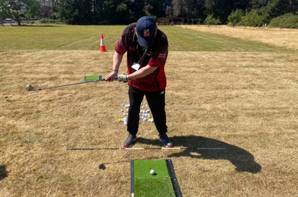 A man taking a golf swing on a putting mat