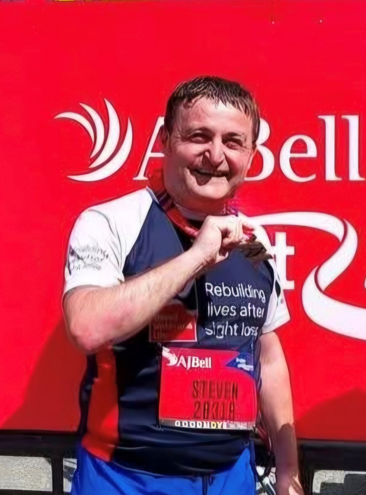 Blind veterans Steven after completing a 10km race holding his medal and smiling