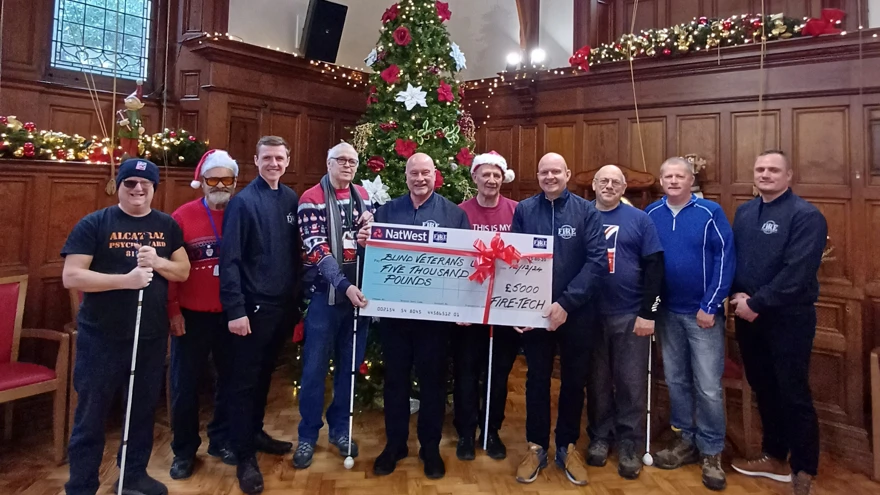 A group of men stand in front of a christmas tree holding a big cheque