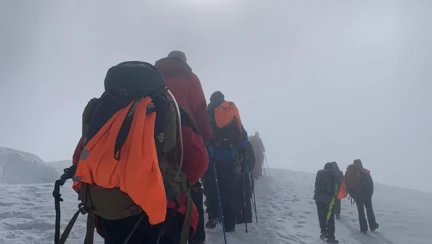 The group of climbers use walking poles to help them through the snow and ice near the top of Mount Kilimanjaro