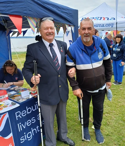 Two blind veterans standing at the Blind Veterans UK stall