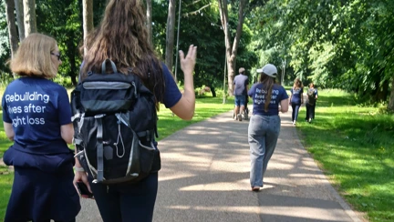 The group of volunteers walk together along a shaded pathway
