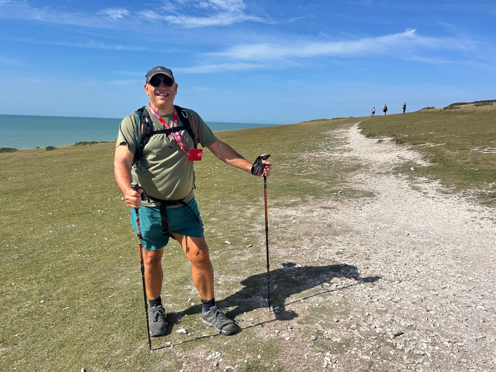 Blind veteran Jerry on the coastal path on a sunny day. The sea is behind him.