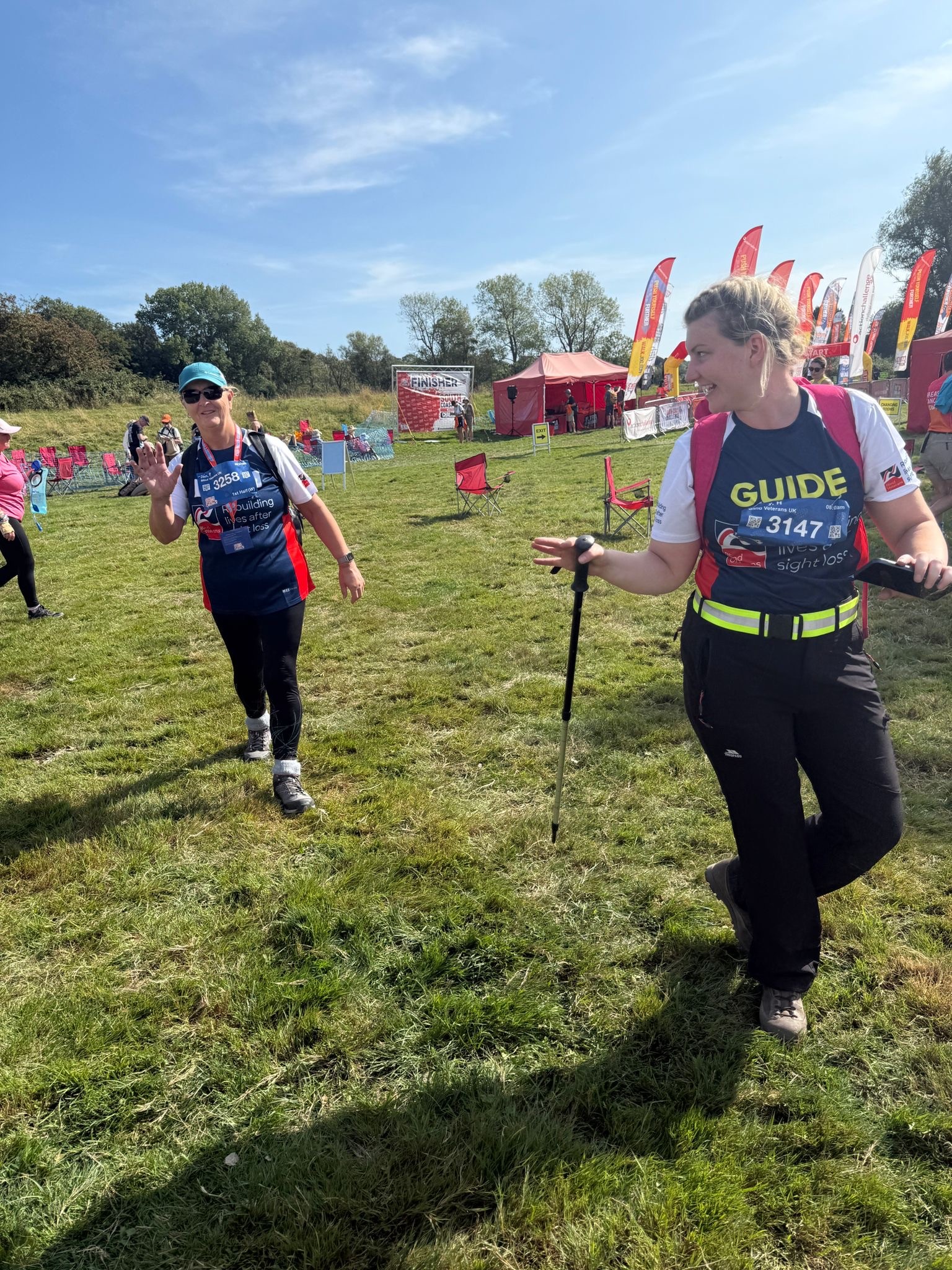 Jan and Poppy in their Blind Veterans UK T-shirts. Poppy is walking slightly ahead of Jan and turning back to talk to her