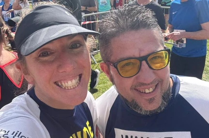 Wayne and Theresa taking a selfie at the start of the race. Both wearing Blind Veterans UK t-shirts. Wayne's t-shirt has his name on it and Theresa's says 'guide'.