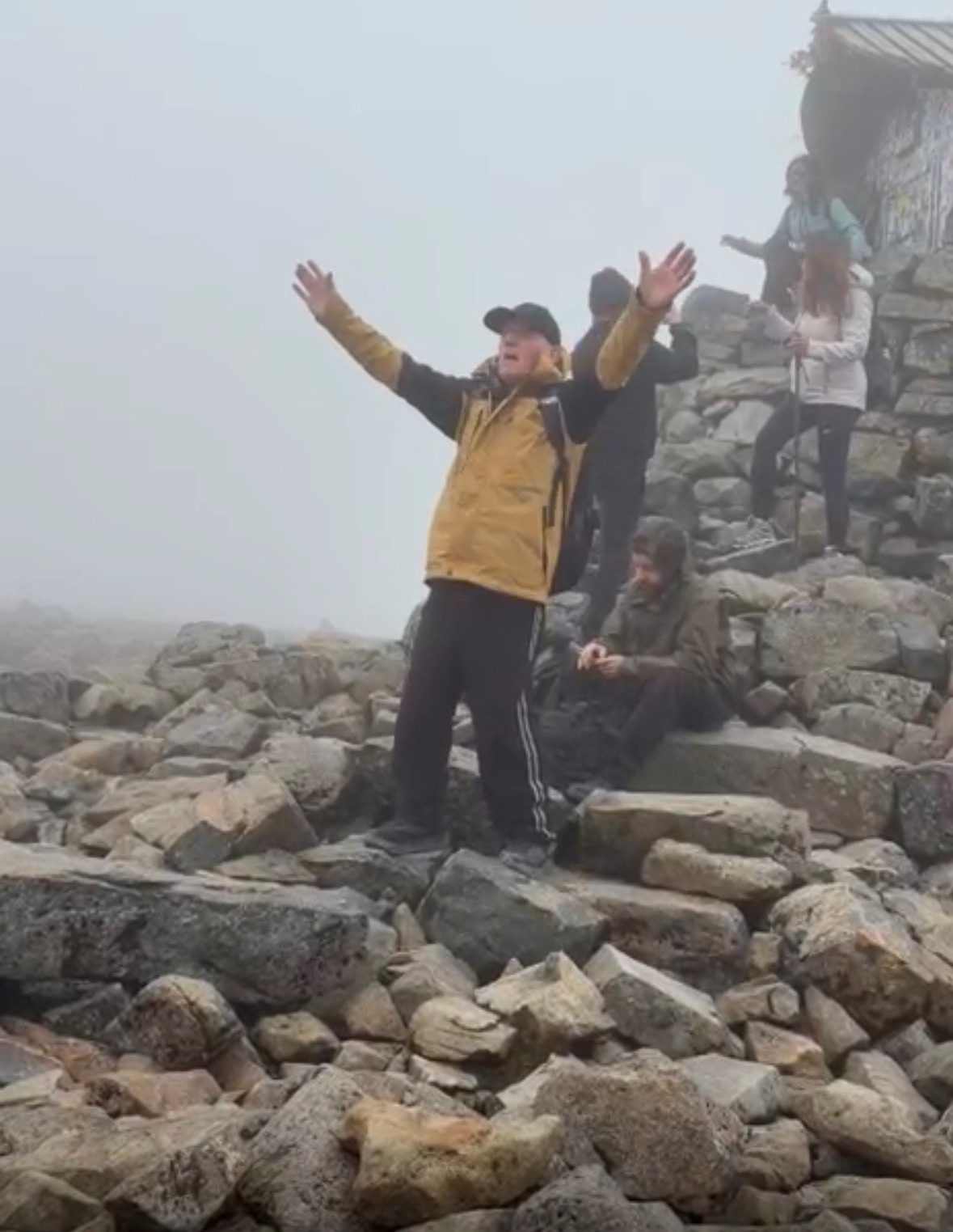 John with his hands in the air celebrating reaching the top of Ben Nevis