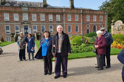 Blind veterans enjoying their day out to Erddig in North Wales - The group stand in front of a grand house in the gardens