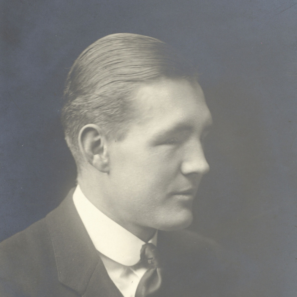 Black and white portrait photograph of former Blind Veterans UK chair, Ian Fraser in a suit against a black background.