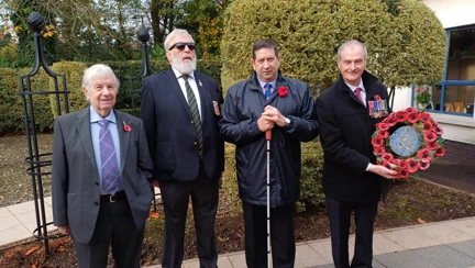 Four blind veterans and another man who is holding a wreath of poppies