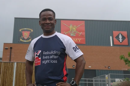 Adi stood in front of an Army building wearing his Blind Veterans UK t-shirt.