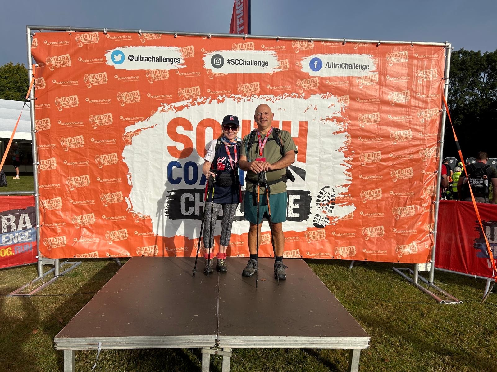 Jerry and Anne stood on a stage with a South Coast Ultra banner in the background